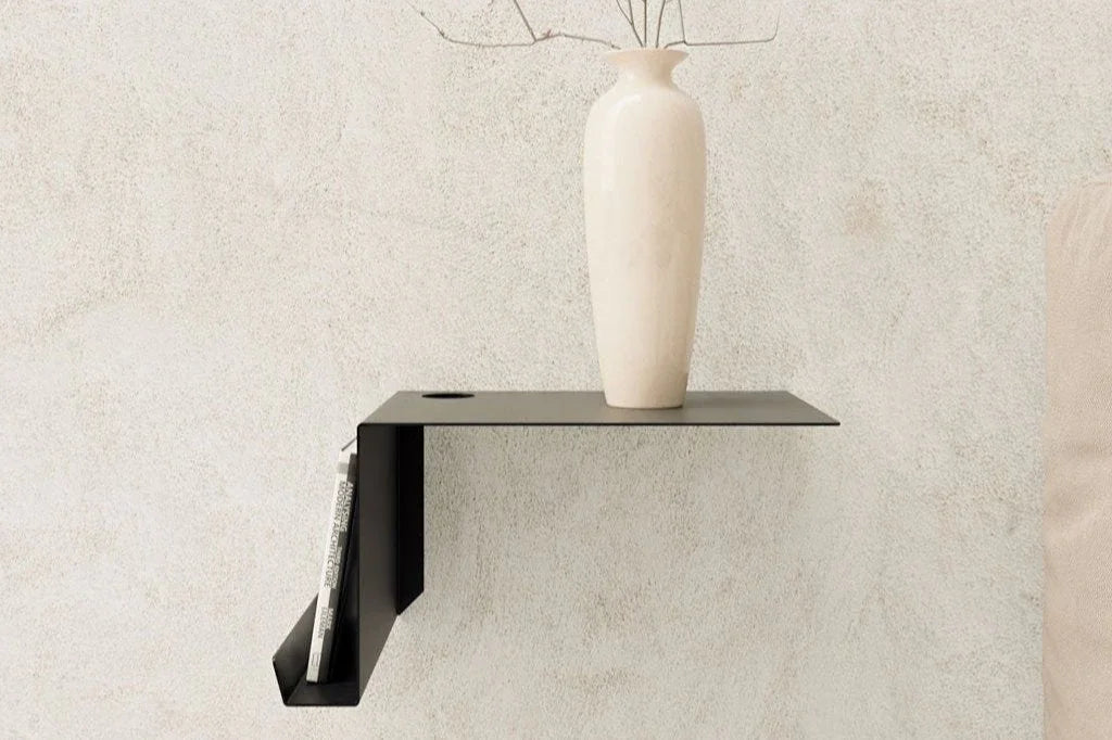 Estante flotante negro de diseño minimalista con jarrón blanco y revista, sobre pared beige