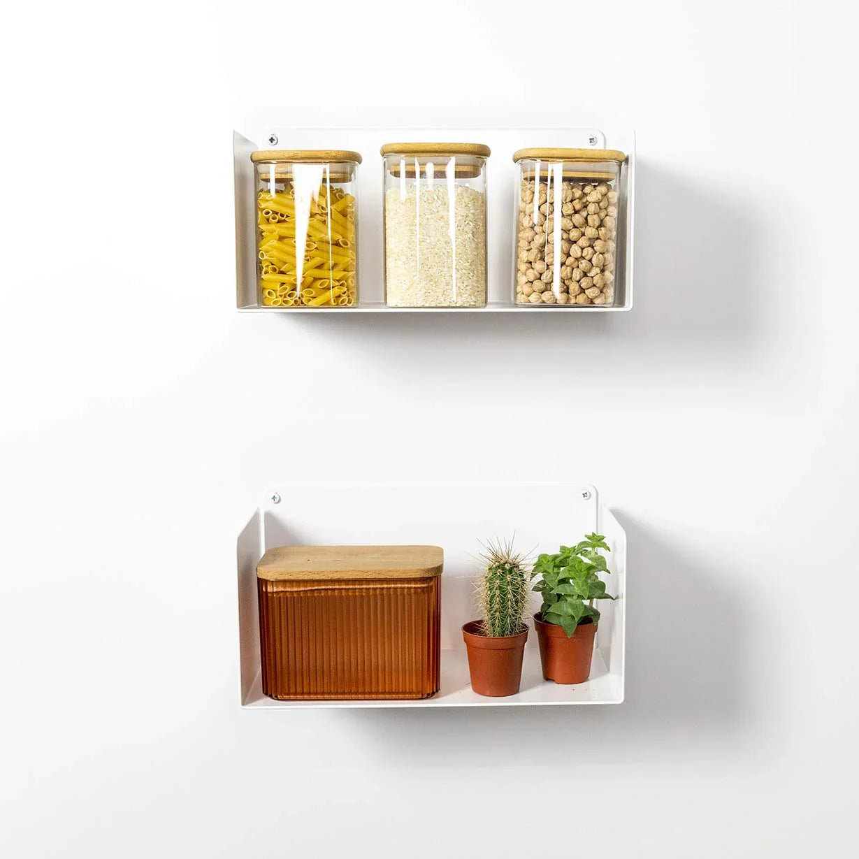 Estantes flotantes blancos en cocina, con tarros de vidrio, plantas y recipiente decorativo