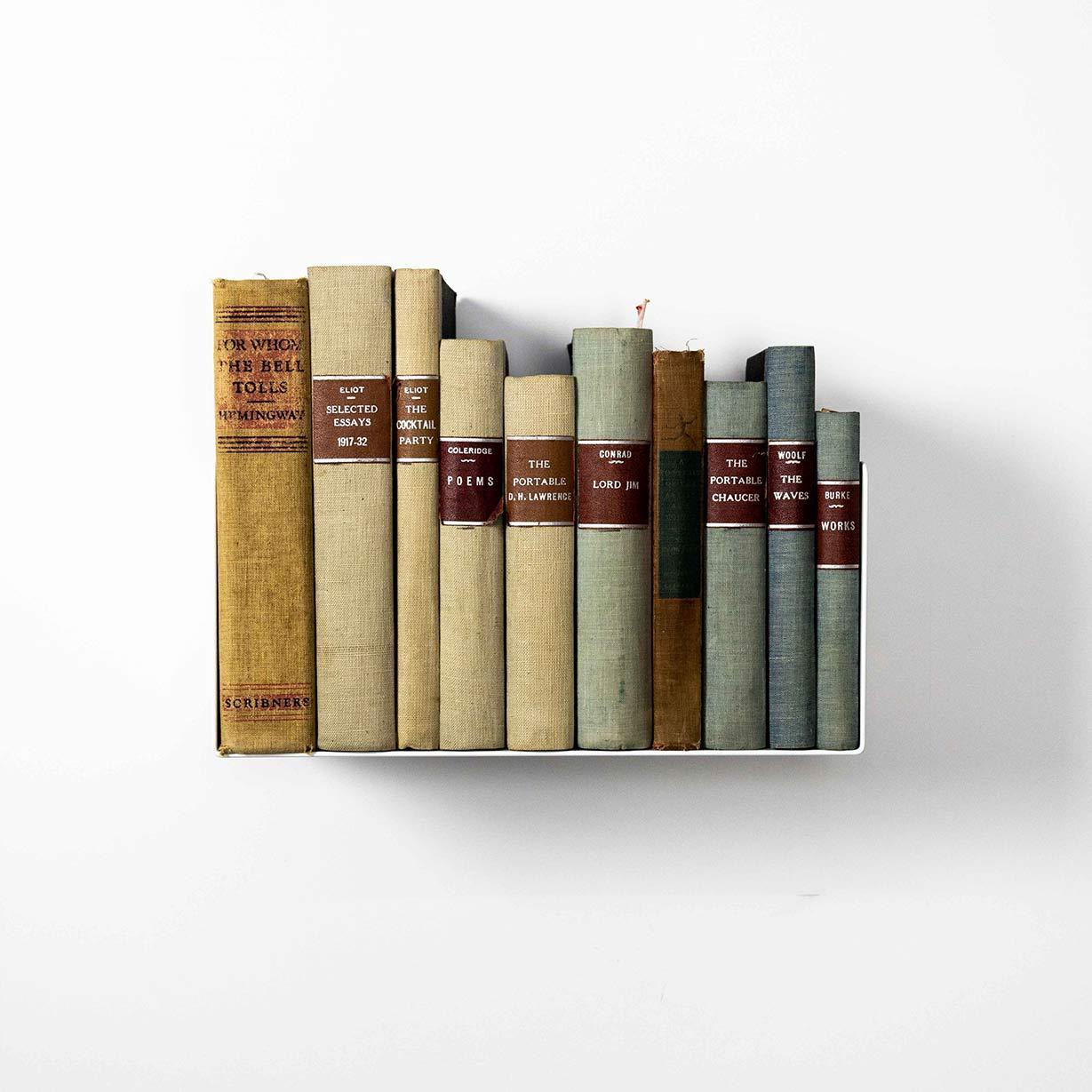 Estante flotante blanco minimalista con libros clásicos sobre pared blanca