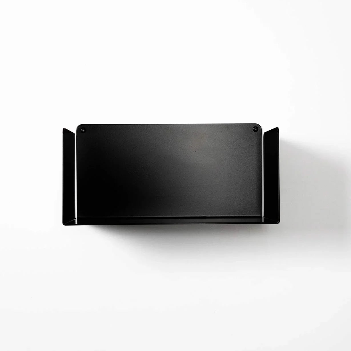 Estante flotante negro de diseño minimalista sobre pared blanca