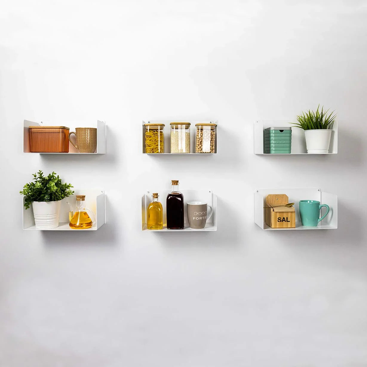Estantes flotantes blancos de diseño minimalista en cocina, decorados con tarros, tazas y plantas.