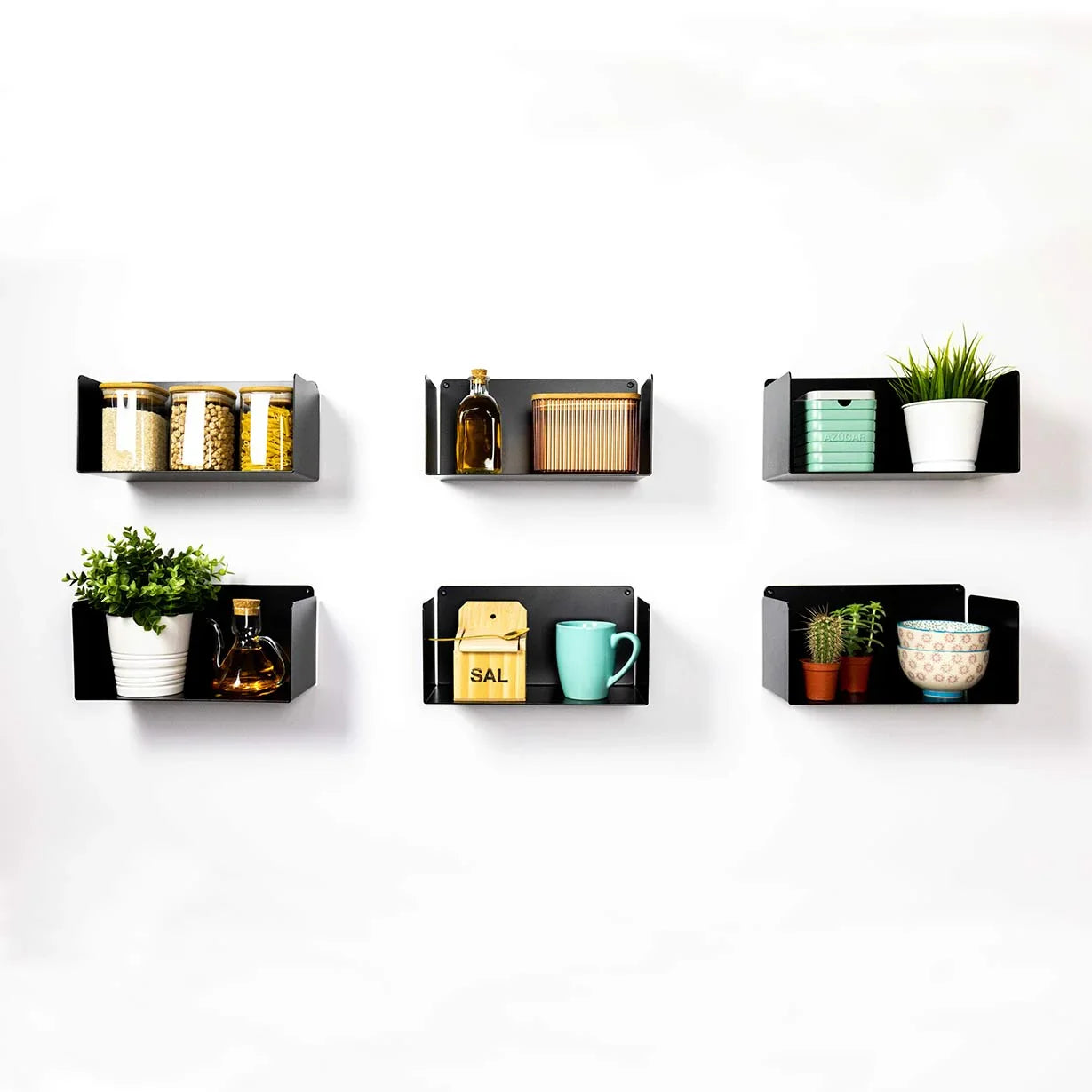 Estantes flotantes de metal negro en cocina minimalista con plantas y utensilios decorativos.