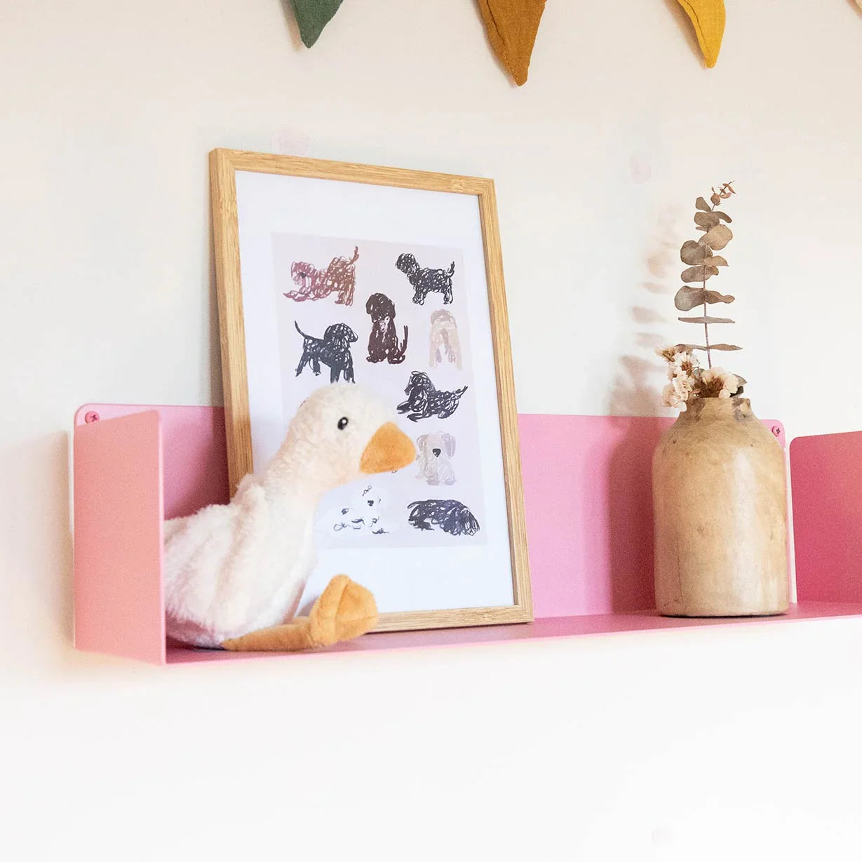 Estantería color rosa colgante en la pared con jarrón, fotos y decoración moderna y original